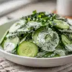 Creamy cucumber dill salad with red onion in a white ceramic bowl