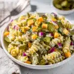 Creamy dill pickle pasta salad in a white bowl with fresh ingredients.
