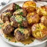 Creamy garlic butter steak bites and potatoes in a rustic cast iron skillet.