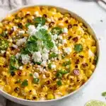 Creamy Mexican street corn dip with cotija cheese and cilantro garnish.