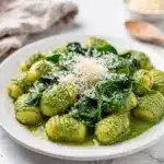 Creamy pesto gnocchi with spinach in a white ceramic bowl.