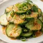 Creamy spicy Asian cucumber salad in a white bowl with chili crisp