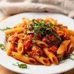 Creamy tomato basil pasta with penne in a glossy sauce and fresh basil.
