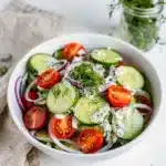 Creamy cucumber dill salad with fresh tomatoes in a bright white bowl