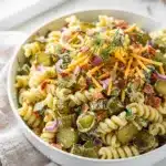 Creamy dill pickle pasta salad with rotini, cheddar, bacon, and fresh dill.