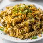 Creamy dill pickle pasta salad with rotini and cheddar cheese in a bowl.