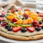 Easy sugar cookie fruit pizza with cream cheese frosting and fresh colorful berries