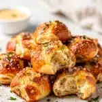 Golden brown garlic parmesan pretzel bites on a rustic wooden board.