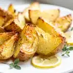Crispy Greek lemon potatoes with oregano on a rustic white platter.
