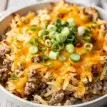 Homestyle crockpot sausage hashbrown casserole with cheese and green onions.
