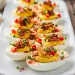 Classic deviled eggs with creamy filling and crispy bacon bits on rustic board