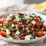 Colorful chopped Mediterranean lentil salad in a white bowl with feta cheese