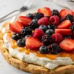 Colorful berry fruit pizza on sugar cookie crust with creamy cheesecake filling.