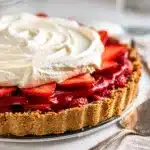 No bake strawberry pie with fresh berries and whipped cream on graham crust.