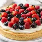 Homemade berry cheesecake fruit pizza with fresh strawberries blueberries raspberries and blackberries.