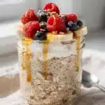 Creamy high protein overnight oats with fresh berries and honey in a jar.