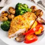 Crispy parmesan crusted chicken with roasted potatoes and vegetables on sheet pan.