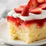 Classic strawberry jello poke cake slice with vibrant red gelatin filling and whipped topping