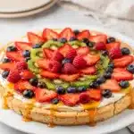 Colorful fruit pizza dessert with sugar cookie crust and creamy frosting.