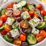 Vibrant tomato cucumber feta salad with olives and fresh dill in a bowl.