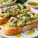 Avocado and white bean bruschetta on toasted baguette slices with olive oil.