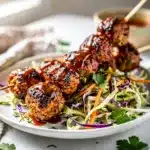 Grilled turkey meatball skewers with sticky sweet barbecue glaze on white plate.