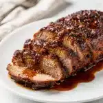 Juicy pork tenderloin with sticky brown sugar barbecue glaze on white plate