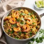 Creamy coconut lime shrimp and rice with peas and fresh cilantro garnish.