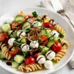 Creamy cucumber caprese pasta salad with mozzarella pearls and balsamic glaze