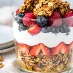 Greek yogurt granola parfait with fresh berries in a clear glass jar.
