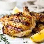 Grilled lemon herb chicken thighs with crispy char marks and fresh rosemary