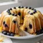Golden lemon blueberry bundt cake with glossy lemon glaze dripping.
