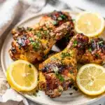 Lemon herb grilled chicken drumsticks with crispy skin and fresh lemon garnish