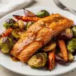 Sheet pan maple Dijon salmon with roasted vegetables on parchment lined baking sheet.
