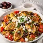Mediterranean chicken orzo skillet with tomatoes olives and feta in cast iron pan