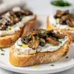 Creamy goat cheese and sautéed mushroom bruschetta on rustic toasted baguette slices.