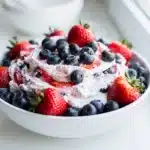 Creamy cheesecake dip with fresh strawberries and blueberries for July Fourth.