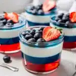 Red white blue layered jello cups with fresh berries.