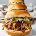 Smoky BBQ pulled chicken sliders with coleslaw and a pickle spear