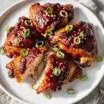 Sticky Korean gochujang chicken thighs with green onions and sesame seeds.