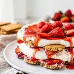 Layered strawberry shortcake icebox cake slice with whipped cream and berries