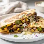 Street corn black bean quesadilla sliced open revealing melted cheese filling.